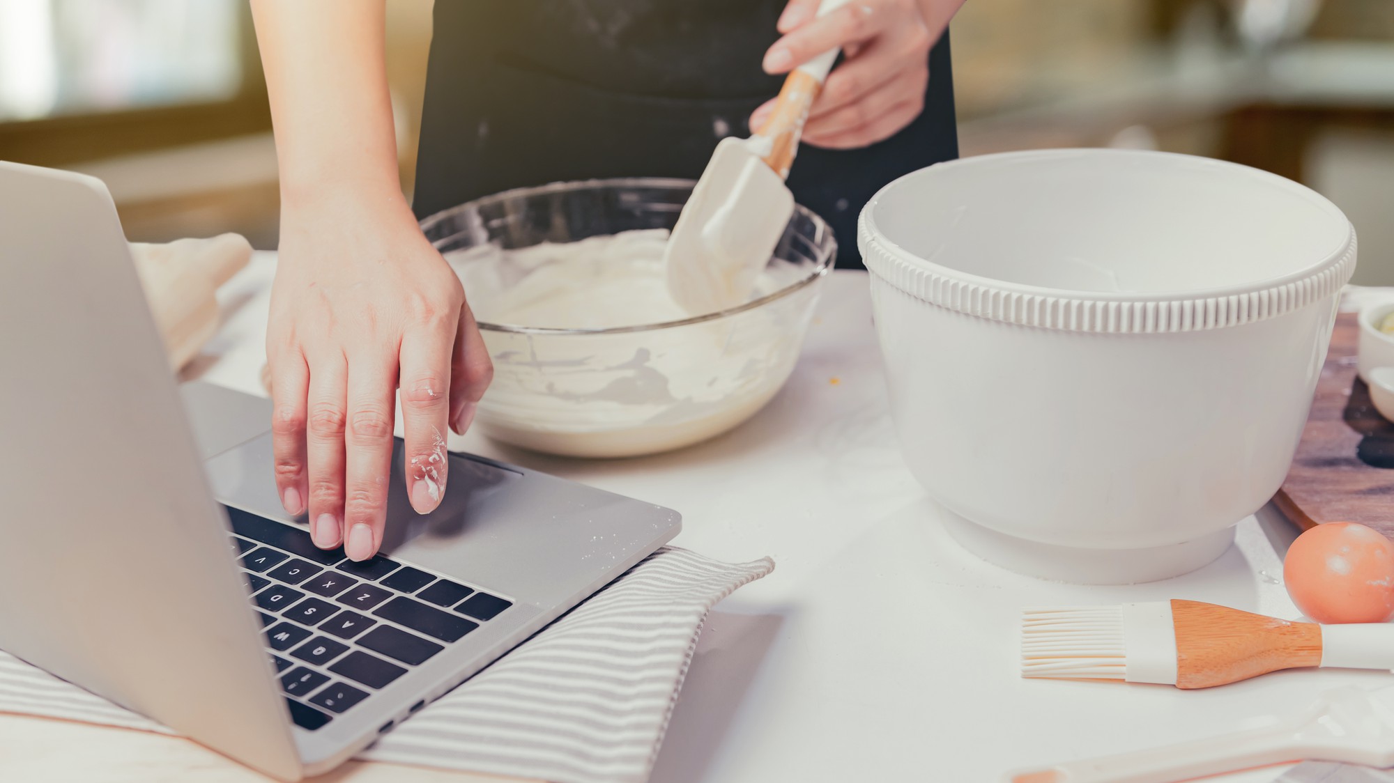 Dettaglio su mani che impastano con strumenti digitali vicino a laptop